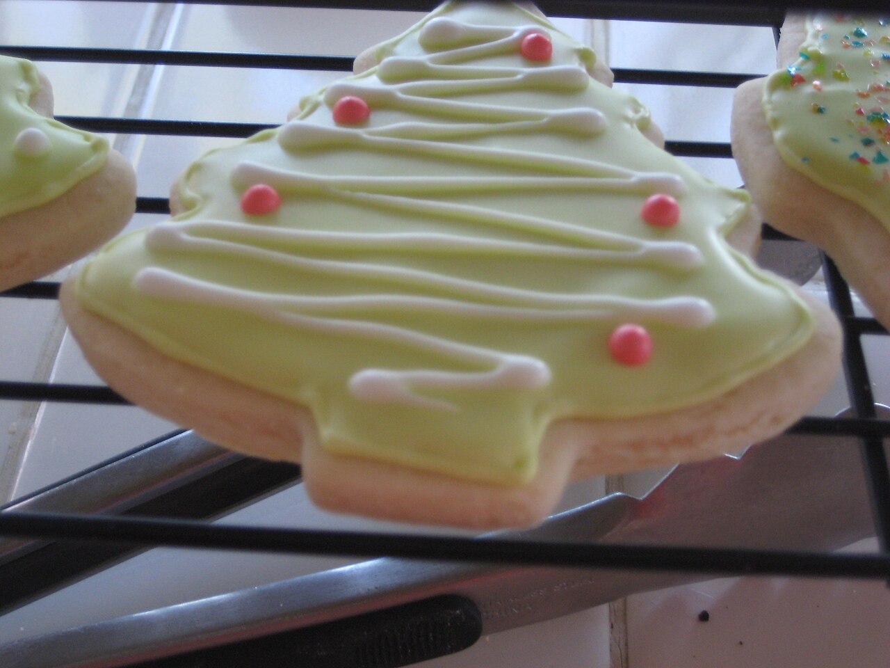 Christmas tree shaped sugar cookie covered with pale green royal icing